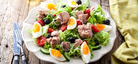 Tuna salad with lettuce, eggs and tomatoes on dark wooden table.の写真素材