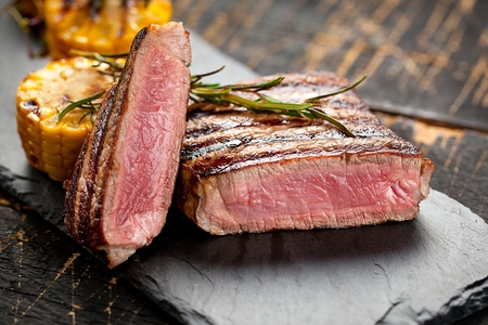 medium grilled steak on dark table with griled cornの写真素材