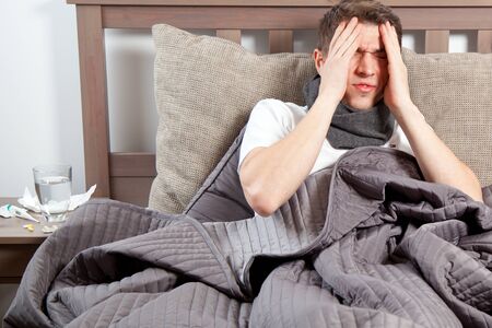 Man feeling bad lying in the bed and coughingの写真素材