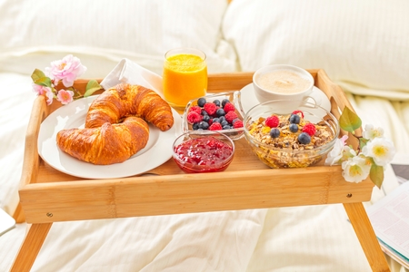 breakfast in bed with fruits and pastries on a tray