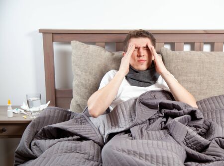 Man feeling bad lying in the bed and coughingの写真素材