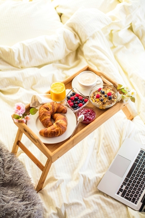 breakfast in bed with fruits and pastries on a trayの写真素材