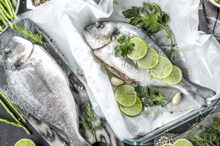 Fresh raw sea bream fish cooking on black stone countertop, top view.の写真素材