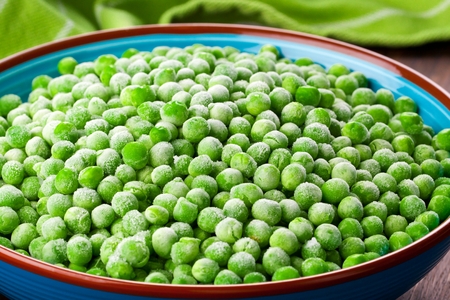 Heap of frozen pea on a old wooden table, top view.の写真素材