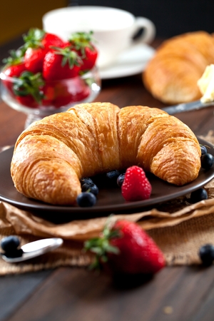 Delicious breakfast with fresh croissants and ripe berries on old wooden background,の写真素材
