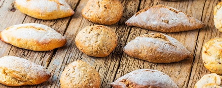 Different kinds of fresh bread on wooden table. Isolated assortment of bread on brown background.