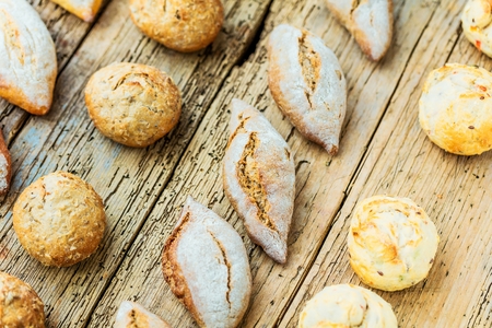 Different kinds of fresh bread on wooden table. Isolated assortment of bread on brown background.の写真素材