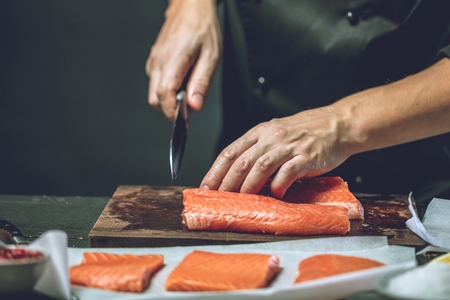 Close up chef putting salt on salmon slice.