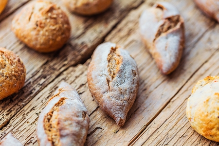 Different kinds of fresh bread on wooden table. Isolated assortment of bread on brown background.