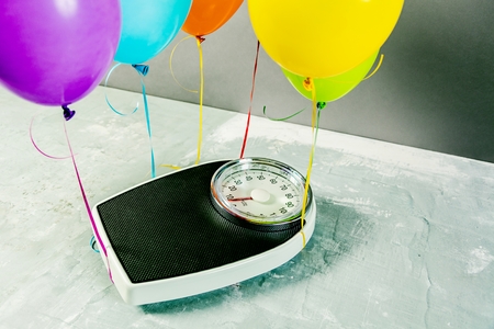 Bathroom scales with colorful balloons. Slimming concept.