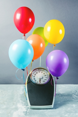 Bathroom scales with colorful balloons. Slimming concept.の写真素材