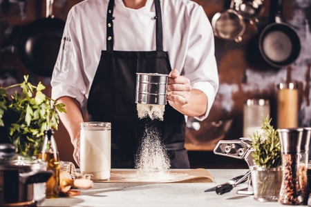 Closeup photo of baker cracking egg for dough. Retro styled imagery.