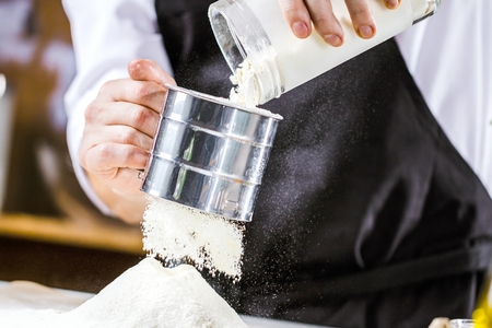 Closeup photo of baker cracking egg for dough. Retro styled imagery.