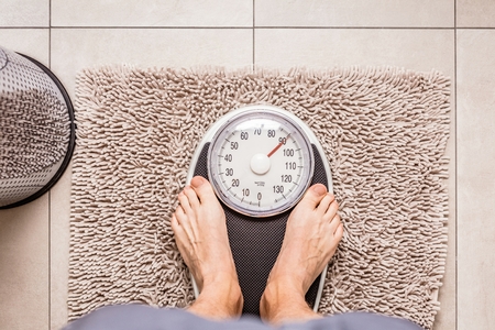 Close-up Weighing Scale, Man standing on weigh scalesの写真素材
