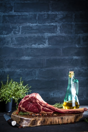 Dry aged raw tomahawk beef steak with ingredients for grillingの写真素材