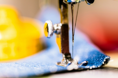 Sewing denim jeans with sewing machine. Repair jeans by sewing machine. Alteration jeans, hemming a pair of jeans, handmade garment industrial conceptの写真素材
