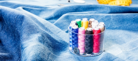 background table top view of sewing tool and jeans on denim fabric.