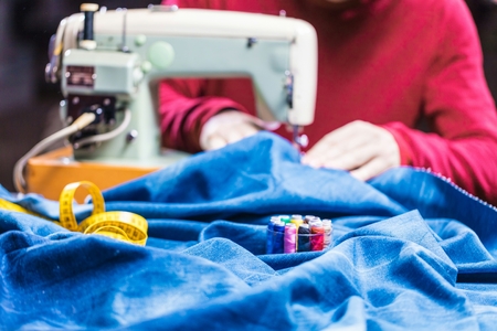 Sewing denim jeans with sewing machine. Repair jeans by sewing machine. Alteration jeans, hemming a pair of jeans, handmade garment industrial conceptの写真素材