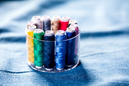 Fabric of various types and objects for sewing. Multicolored fabric, thread reels, needles, a sewing...