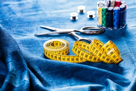 background table top view of sewing tool and jeans on denim fabric.