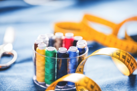 Fabric of various types and objects for sewing. Multicolored fabric, thread reels, needles, a sewing paw are needed for sewing clothes.の写真素材