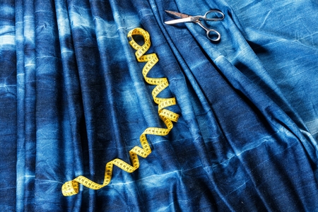 background table top view of sewing tool and jeans on denim fabric.