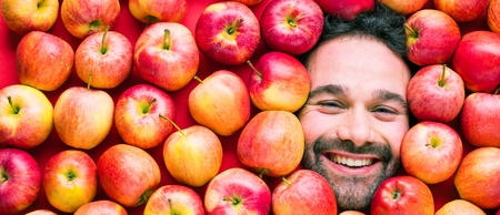 Food industry. Face of laughing man in apple plane. Creative background with apples for your productの写真素材