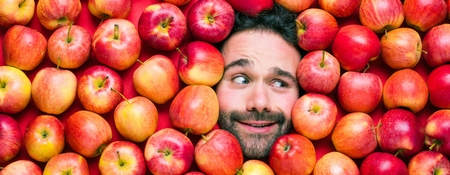 Food industry. Face of laughing man in apple plane. Creative background with apples for your productの写真素材