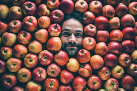 Food industry. Face of laughing man in apple plane. Creative background with apples for your productの写真素材
