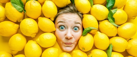 Woman with lemons, concept for food industry. Face of laughing woman in lemon surfaceの写真素材