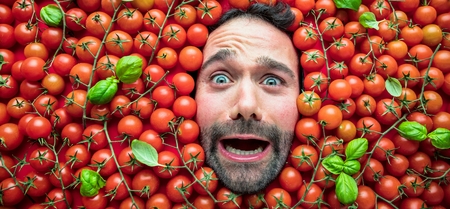 Man with tomatoes, concept for food industry. Face of emotional man in tomato surface