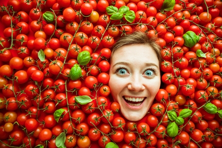 Woman with tomatoes, concept for food industry. Face of laughing woman in tomato surface.の写真素材