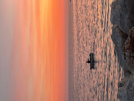 Silhouette of a man in a boat on the sea at sunsetの写真素材