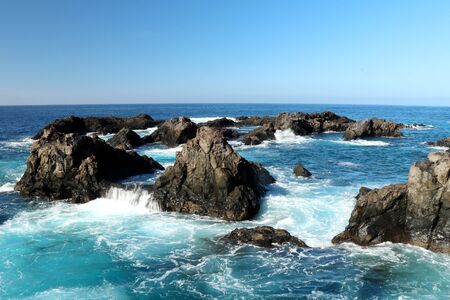 A ring of rocks made of lava in the bright blue water of the Atlantic Ocean on a beach inLos Gigantes, Spain on the island of Tenerife in the Canary Islands on a hot winter day in December.のeditorial素材