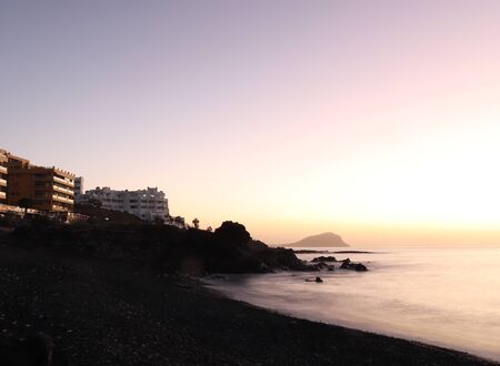 Colorful water and sky next to resorts on the beach during sunrise over the Atlantic Ocean in Tenerife, Spain on the Canary Islands.のeditorial素材