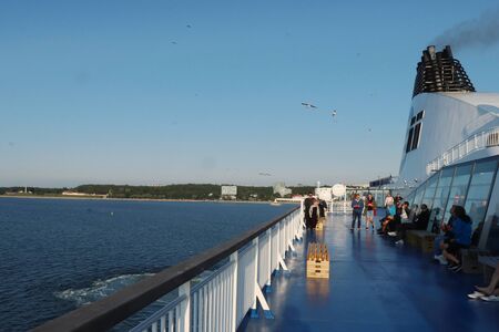 Ferry deck on the Baltic Sea near Tallinn, Estonia with people, seagulls and a smoke stack on a summer evening in July.のeditorial素材