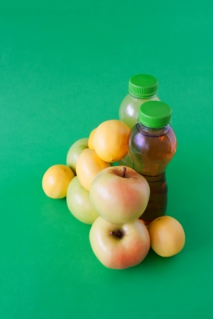 Fresh apples and lemons, and two bottles of apple juice  Green background の写真素材