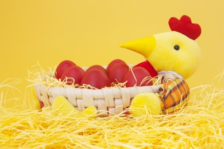 Red easter eggs in a basket, on yellow backgroundの写真素材