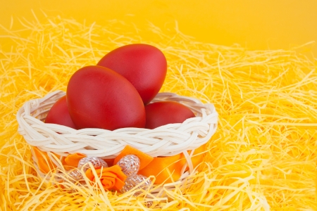 Red easter eggs in a basket, on yellow backgroundの写真素材