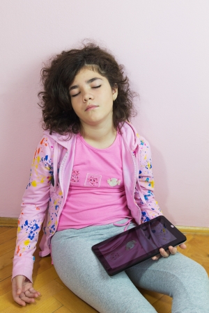 Asleep young girl with a tablet pc in handの写真素材