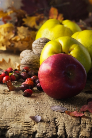 Autumn composition of apples, quince, and dry branches on wooden table の写真素材
