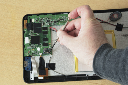Process of PC Tablet Device Repair on a Wooden Table.の写真素材