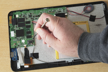 Process of PC Tablet Device Repair on a Wooden Table.の写真素材