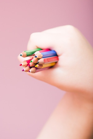 Coloring Pencils in a Hand on a Violet Background. Selective focus.の写真素材