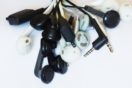 Many diferent old earphones and connectors on white background.の写真素材