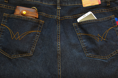 Cellphone and a leather wallet in the back pockets of jeans.の写真素材