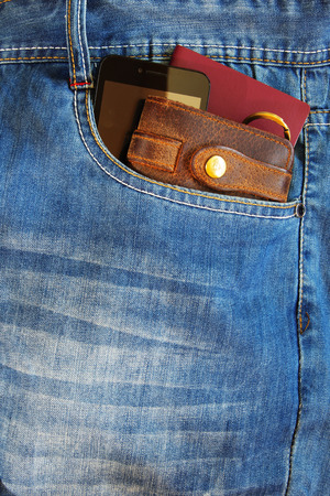 Passport and a leather wallet with modern smartphone in the pocket of old blue jeans.の写真素材