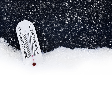 Thermometer in the snow with focus on the red. Both celsius and fahrenheit