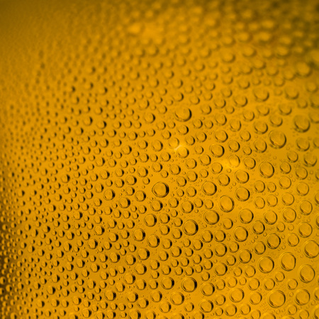 Yellow orange beer drops on a bottle or glass.