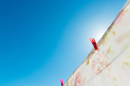 Bed sheet drying on a rope outside. The weather is beautiful and sunny with blue sky.の写真素材